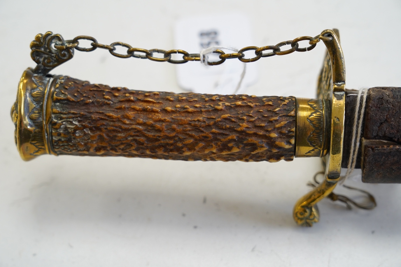 A William III English hunting hanger with pierced brass mounts, stag horn grip, blade struck with king’s head, in its leather scabbard, blade 45cm. Condition - worn, knuckle bow replaced with chain and chape missing to s